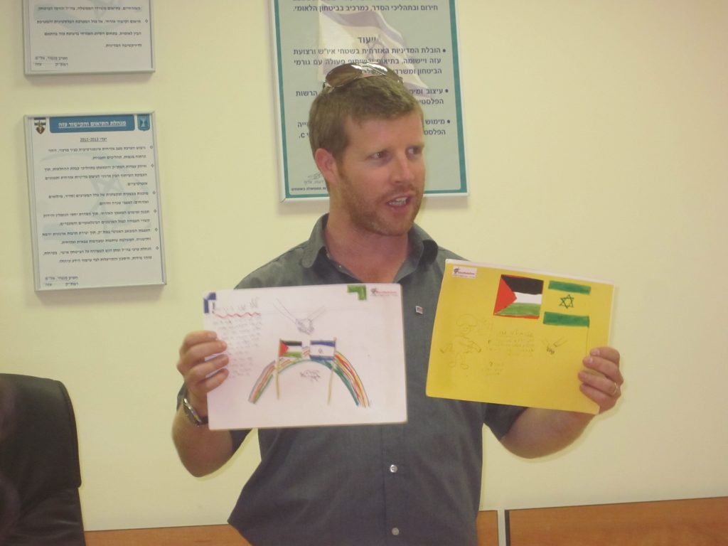 Noam Bedein, Director of the Sderot Media Center holding two drawings made by Israeli children, wishing for peace with their Gazan neighbors.