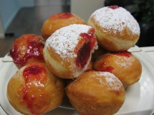 Sufganiya- a round jelly doughnut eaten in Israel and around the world on the Jewish festival of Hanukkah. The doughnut is deep-fried, filled with jelly or custard, and then topped with powdered sugar.
