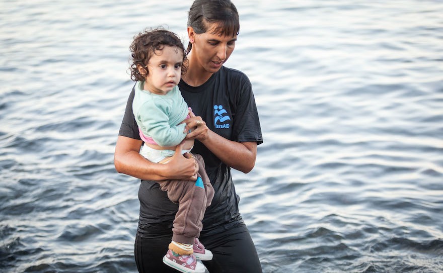 Tali Shaltiel, an Israeli physician, taking a Syrian child from a dinghy that arrived at a beach on the Greek island of Lesbos. (Boaz Arad/IsraAID)