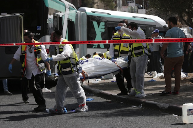 Israeli Zaka volunteers carry a body following a shooting attack on a bus in an east Jerusalem Jewish settlement adjacent to the Palestinian neighbourhood of Jabal Mukaber on October 13, 2015. Two attackers opened fire on a bus while another assailant carried out a car and knife assault in Jerusalem, leaving two people dead and five wounded in two separate incidents, Israeli authorities said. AFP PHOTO / THOMAS COEX (Photo credit should read THOMAS COEX/AFP/Getty Images)