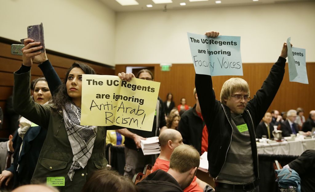 Students hold up protest signs at the end of a public comment period during a University of California Board of Regents meeting in San Francisco, March 23, 2016. (AP/Eric Risberg)