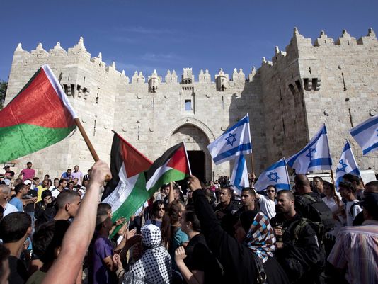 On May 8, 2013, Israelis and Palestinians wave flags as Israelis march celebrating Jerusalem Day outside Damascus Gate in Jerusalem's old city. Source: Sebastian Scheiner, AP